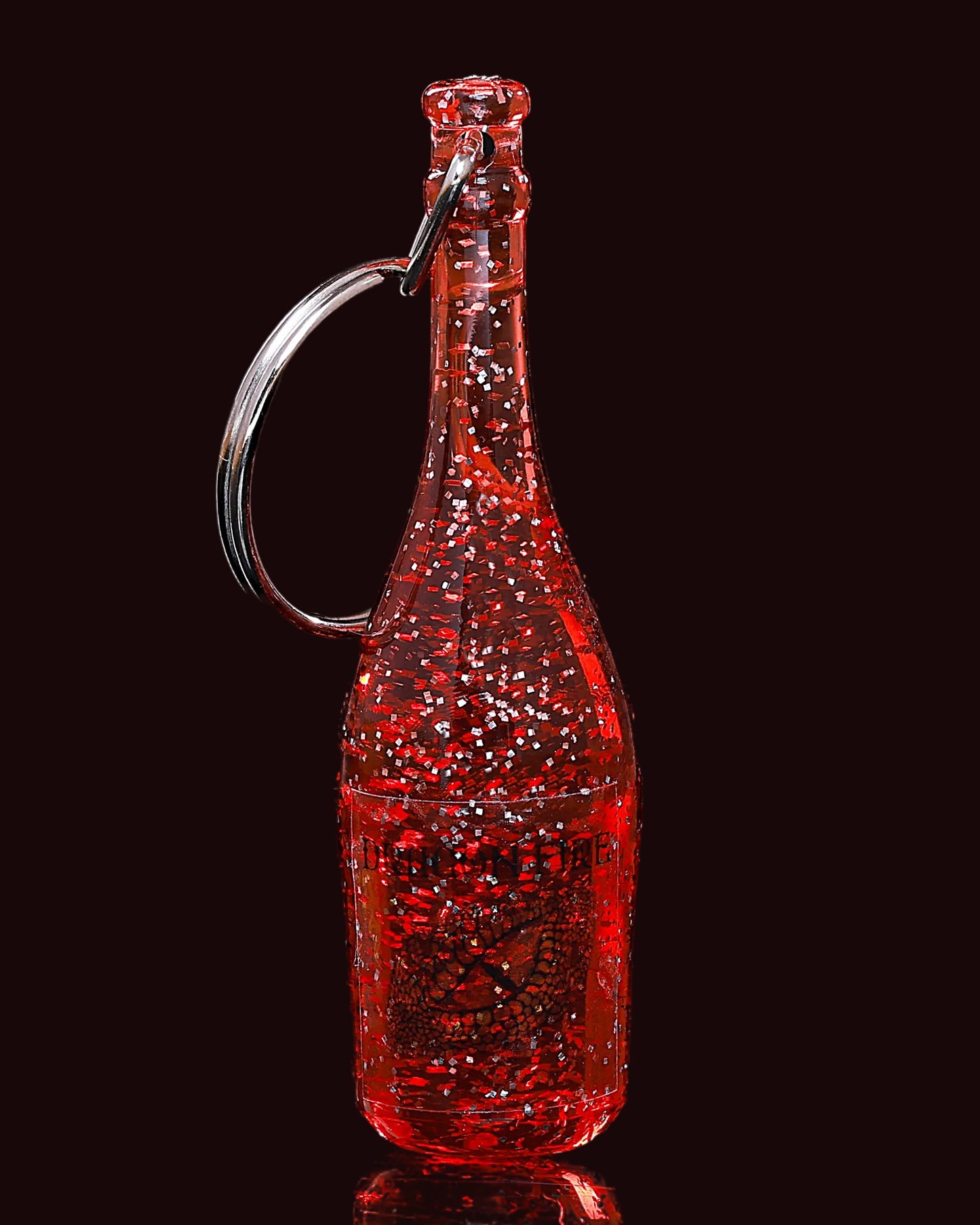Red glittery bottle-shaped keychain on a black background