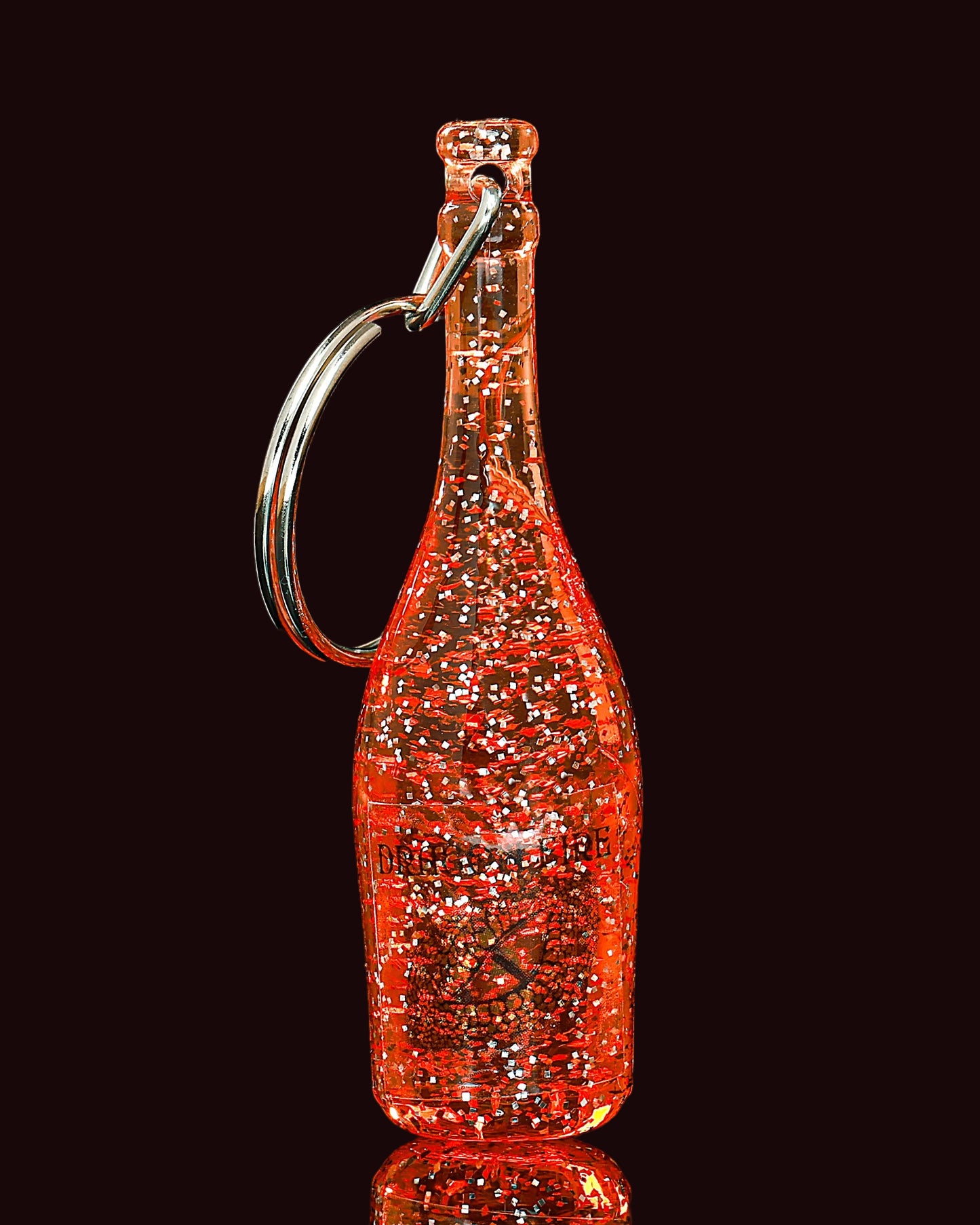 Bottle-shaped keychain with a reflective surface on a black background