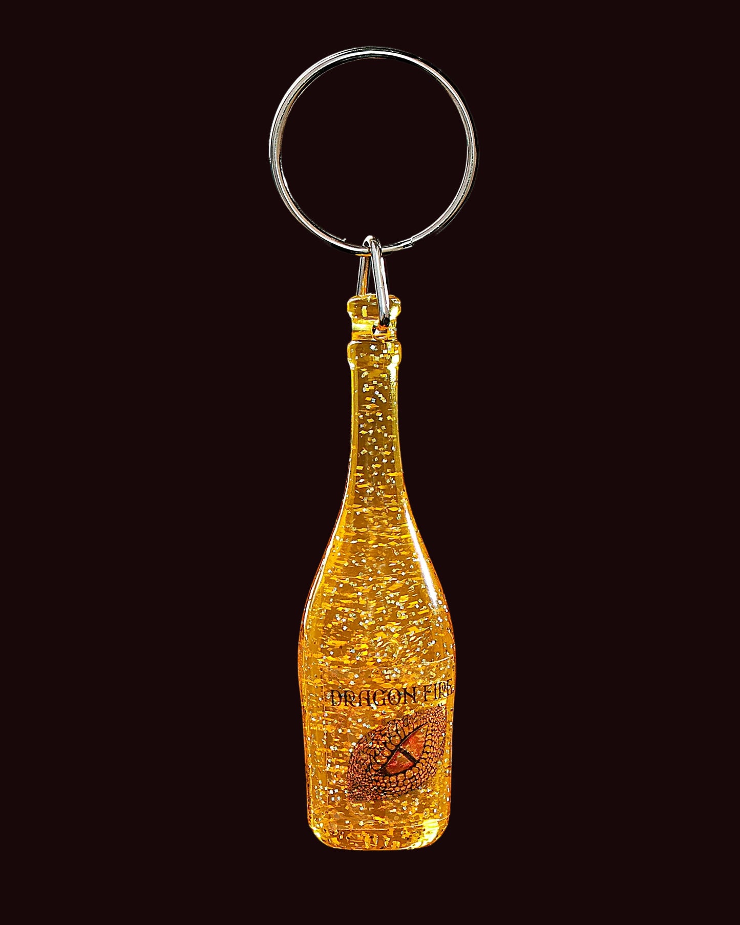 Gold champagne bottle keychain with 'Perelmann' branding on a black background