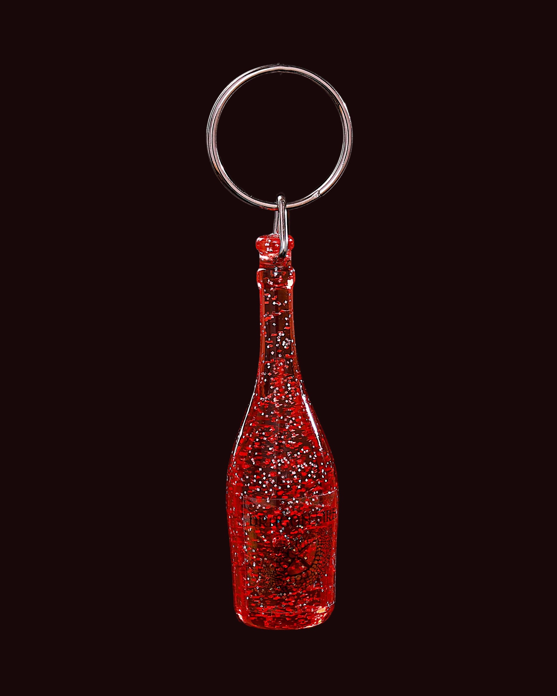 Red glittery bottle-shaped keychain on a black background