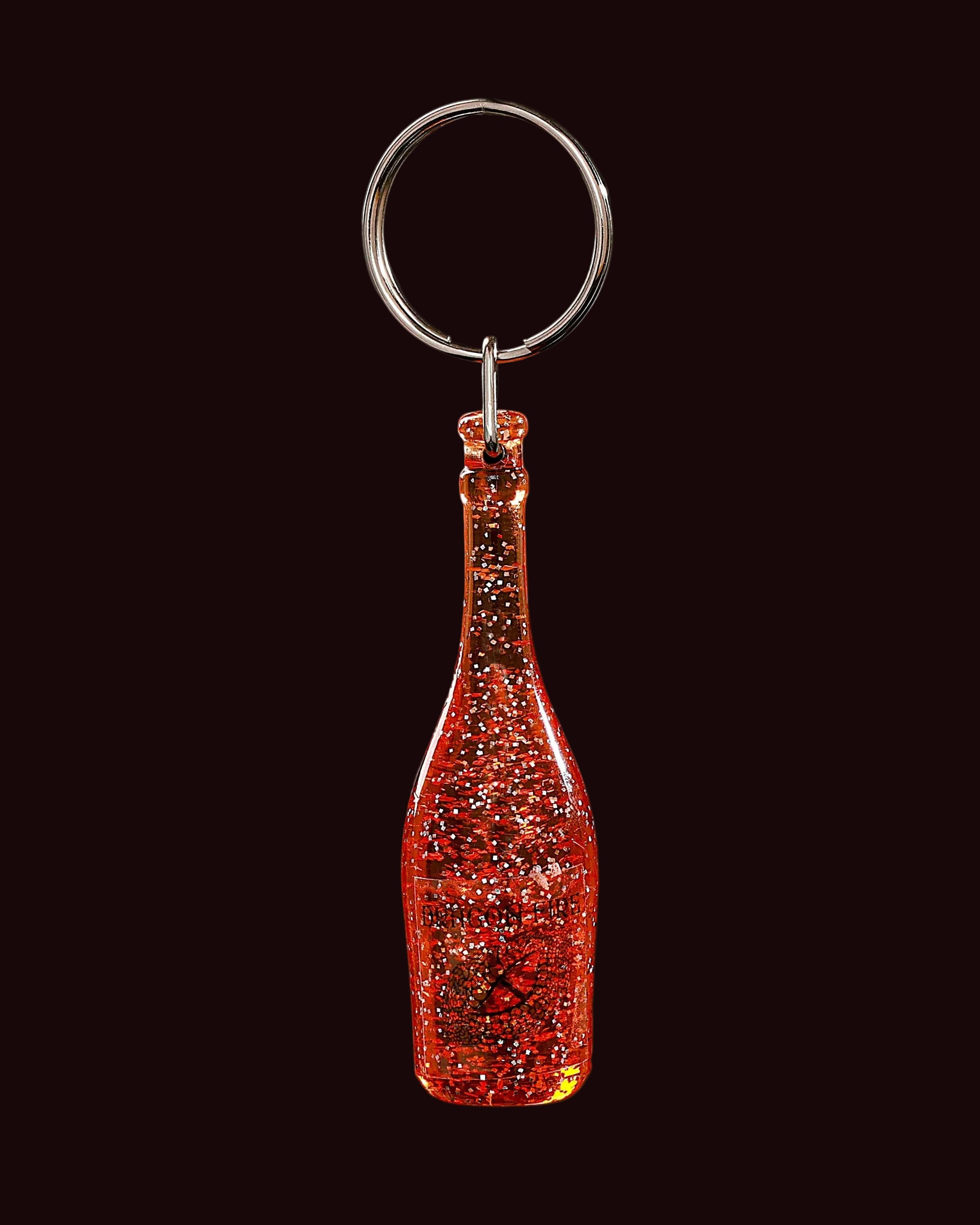 Red glittery bottle-shaped keychain on a black background