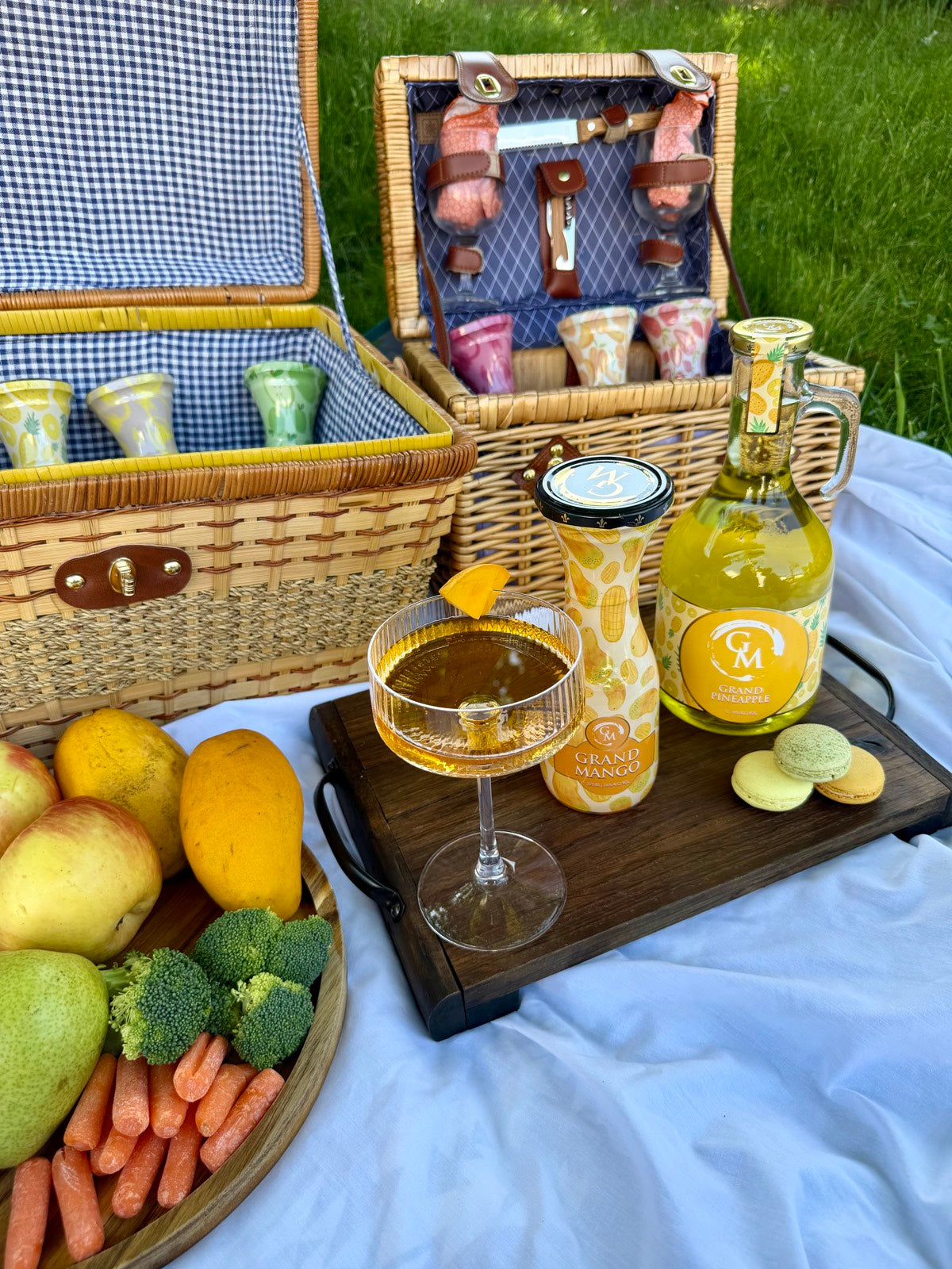 Grand Moscato wine on platter outside with fruits, macaroons and picnic basket on a picnic blanket